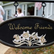 A sign in front of a house welcoming friends to visit.