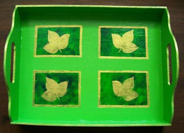 A green decorative tray painted with gold leaves.