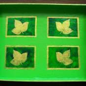 A green decorative tray painted with gold leaves.
