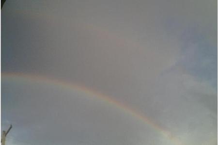 A double rainbow against a cloudy sky.