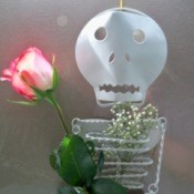 A metal skeleton sculpture with a rosebud.