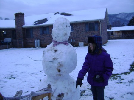 A snowman and a boy in a winter jacket.