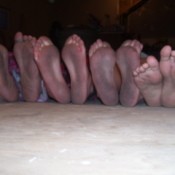 The dirty soles of four girls feet, all in a row.