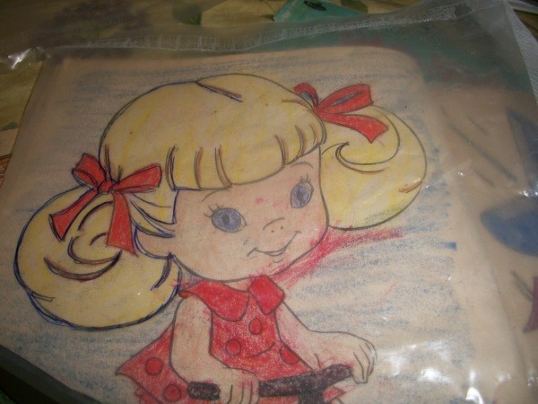 A little girl picture in a coloring book being traced on recycled liners from cereal boxes.