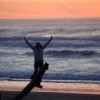 A sunset with a woman with outstretched hands.