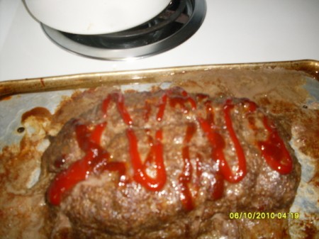 Baked meatloaf with a drizzle of ketchup on top.