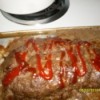 Baked meatloaf with a drizzle of ketchup on top.