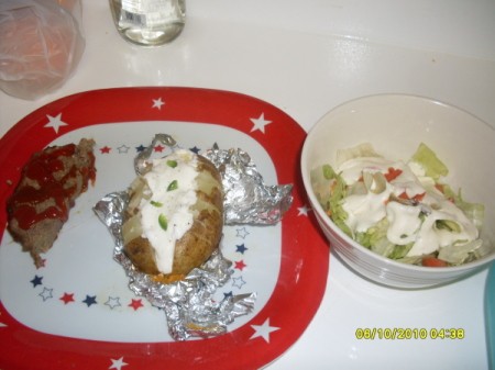 A meatloaf dinner with baked potato and a green salad.