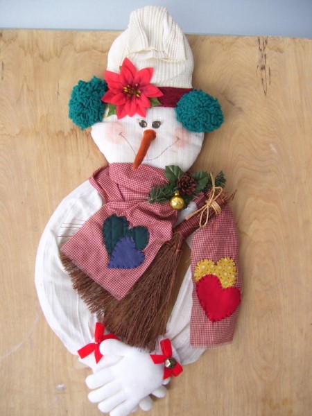 snowman door wreath wearing sweater, knit cap, gloves, and scarf