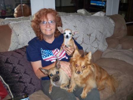 woman sitting on the floor holding three small dogs