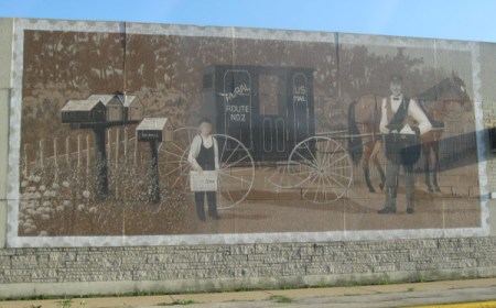 An old fashioned postal scene painted on the side of a post office in Omro, WI.