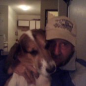 man in baseball cap holding a tricolor dog