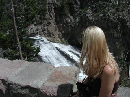 A woman looking out at a waterfall below.