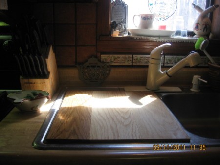 Kitchen sink with wooden cutting board cover