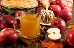 Photo of hot apple cider surrounded by apples.
