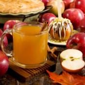 Photo of hot apple cider surrounded by apples.