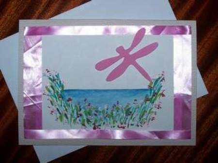 Dragonfly cut out on a card with flowers and a border