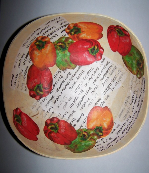 View of interior of bowl with eleven cut outs of bell peppers arranged artfully overlapping each other and the "word" paper pieces.