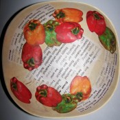 View of interior of bowl with eleven cut outs of bell peppers arranged artfully overlapping each other and the "word" paper pieces.