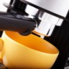 closeup of espresso machine and orange coffee cup