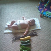 Baby on blanket with veggies placed in front.