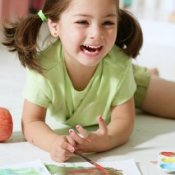 A girl painting a picture on the floor.