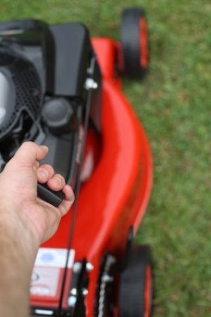 Person pulling starter cord on a red lawn mower.