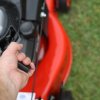 Person pulling starter cord on a red lawn mower.