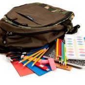 Photo of a back pack, colored pencils, paper and other school supplies.