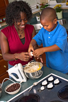 A mother showing her son how to crack an egg.