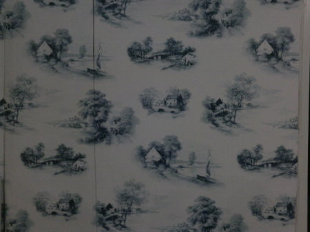 White or cream wallpaper with scattered images of country cottages, stone bridges, and a lake with a sail boat.