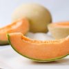 Slice of cantaloupe with other cantaloupes in the background.