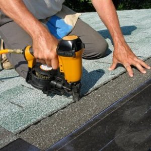 Man nailing up new shingles on a roof.