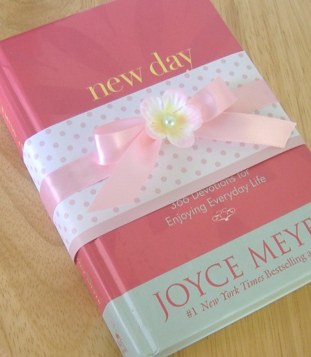 Used Book (New Day) with pink polkadot paper "ribbon" wrapped around the cover, with a pink ribbon tied in a bow and flower on top of it.