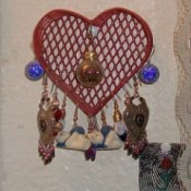 A red wire heart basket for displaying earrings.
