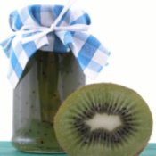 A jar of kiwifruit jam and half of a kiwi.