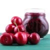 Pile of fresh cherries in front of a jar of cherry jam.