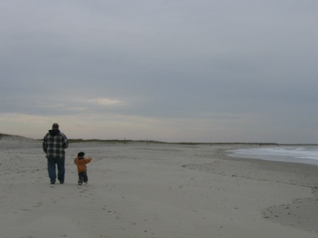 small son running to catch up with his dad on the beach