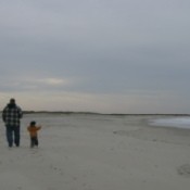 small son running to catch up with his dad on the beach