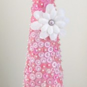 Styrofoam cone covered with pink buttons. The finished cone is sitting in a pedestal candy dish.