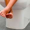 A child's feet sitting on a toilet during potty training.