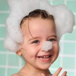 Toddler with bubbles on hair and end of nose.