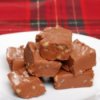 Chocolate fudge with nuts on a white plate on red plaid tablecloth.
