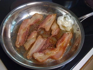 Bacon frying in ban with a wadded up paper towel and little grease.