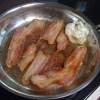 Bacon frying in ban with a wadded up paper towel and little grease.