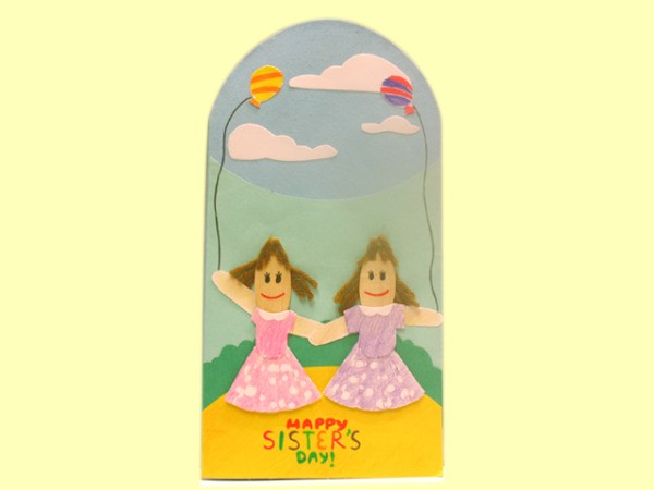 Finished sister card, two popsicle stick girls on a blue background with clouds