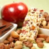 An apple, granola bar, nuts and dark chocolate squares.