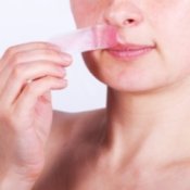 Woman removing a wax strip from her top lip.