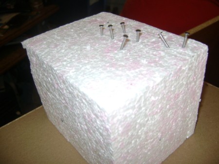 Block of Styrofoam with nails and screws pushed partway into it