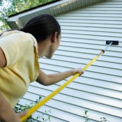 Cleaning Vinyl Siding, A woman scrubbing the siding of her house.